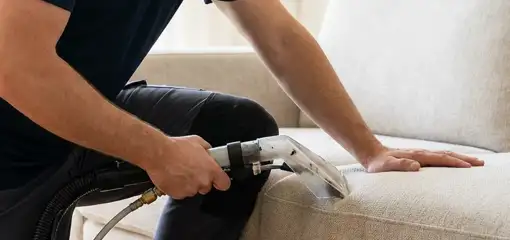 Professional upholstery cleaner deep-cleaning a fabric sofa with a handheld extraction tool, Savannah, GA.